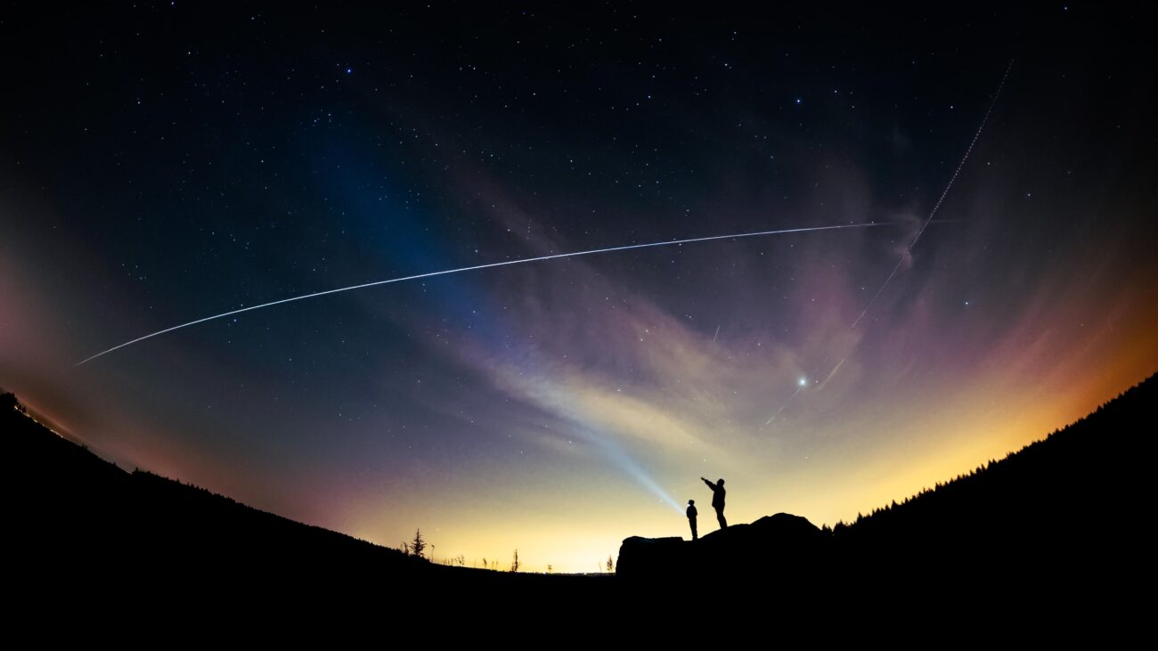 Personas observando el paso de la Estación Espacial Internacional desde la ciudad bajo un cielo estrellado