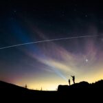 Personas observando el paso de la Estación Espacial Internacional desde la ciudad bajo un cielo estrellado